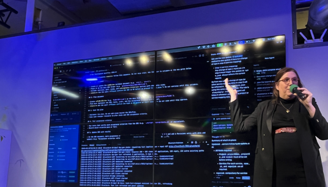Xesca Alabart on the main stage at Agentic Coding Hamburg, speaking with large screens showing a development workflow behind her.