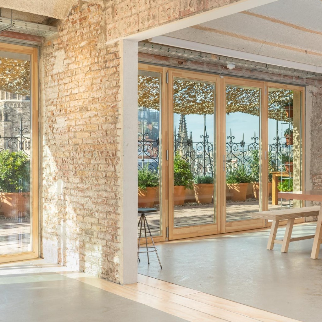 Pier07 terrace in Barcelona — wooden deck, potted plants, and open doors to the terrace with views of the Gothic Quarter cathedral